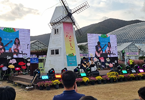 섬꽃축제 풍차 앞에서 노래라는 가수들을 보는 관객들